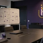 Lege analysekamer van RSC Anderlecht met een tactisch bord en een vast clubembleem aan de muur.