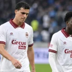 Twee spelers van Royal Antwerp FC in witte wedstrijdshirts op het veld.