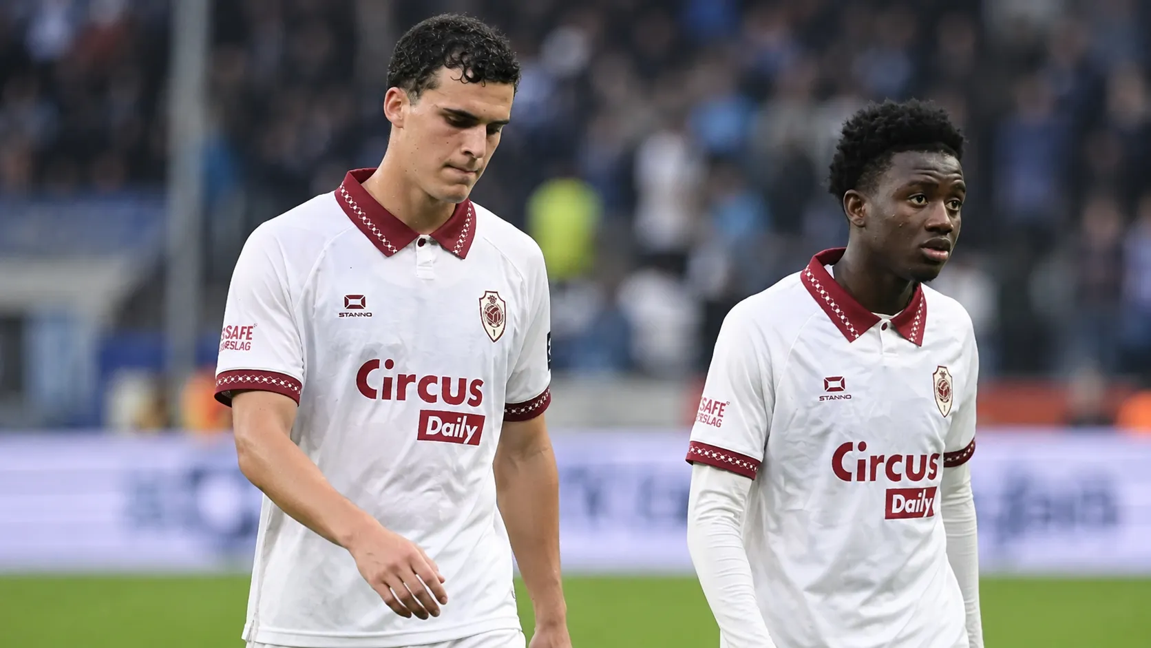 Twee spelers van Royal Antwerp FC in witte wedstrijdshirts op het veld.