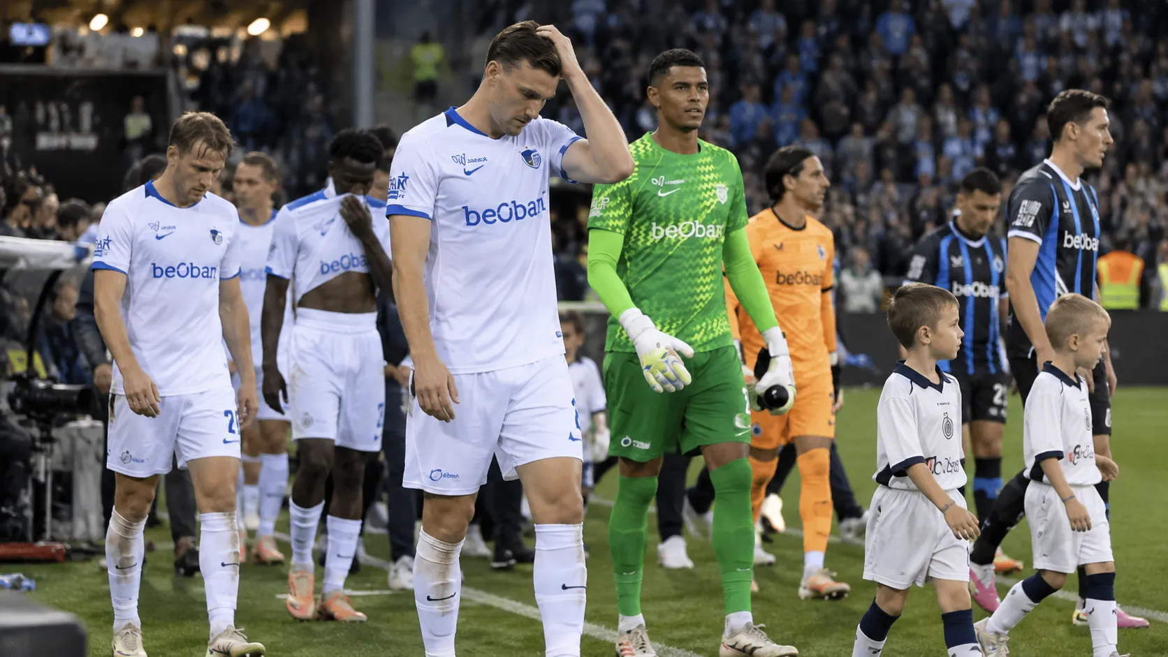 Spelers van Club Brugge en KRC Genk wandelen na de wedstrijd samen van het veld.