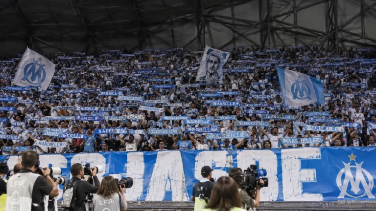 Een grote groep Olympique Marseille-supporters met blauw-witte sjaals in het Vélodrome.