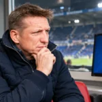 Wesley Sonck in de mediaruimte van een stadion naast een monitor met het embleem van KRC Genk.