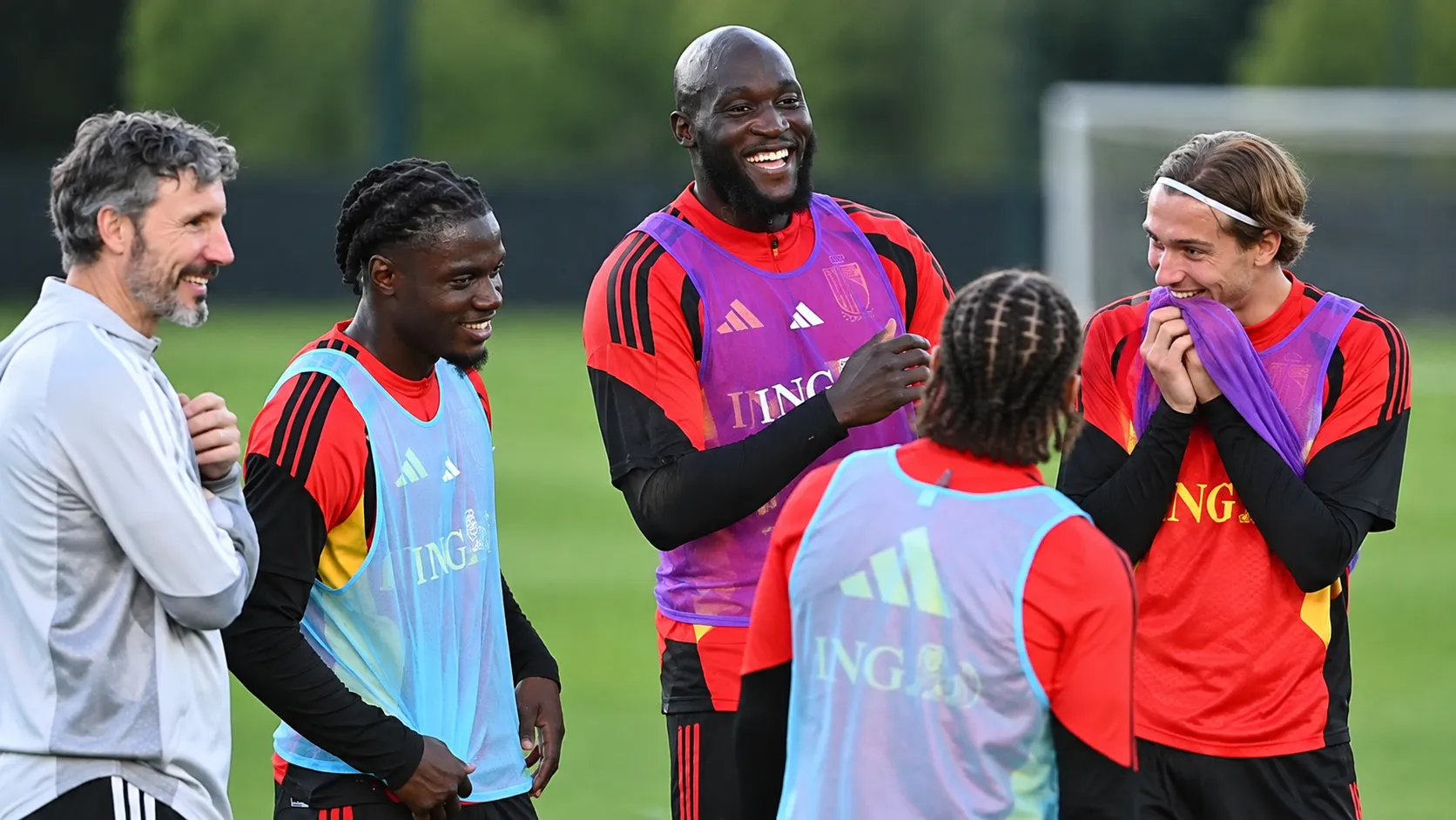Een groep Belgische internationals en stafleden tijdens een ontspannen training op het veld.