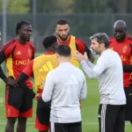 Stafleden spreken met een groep Rode Duivels op het trainingsveld.