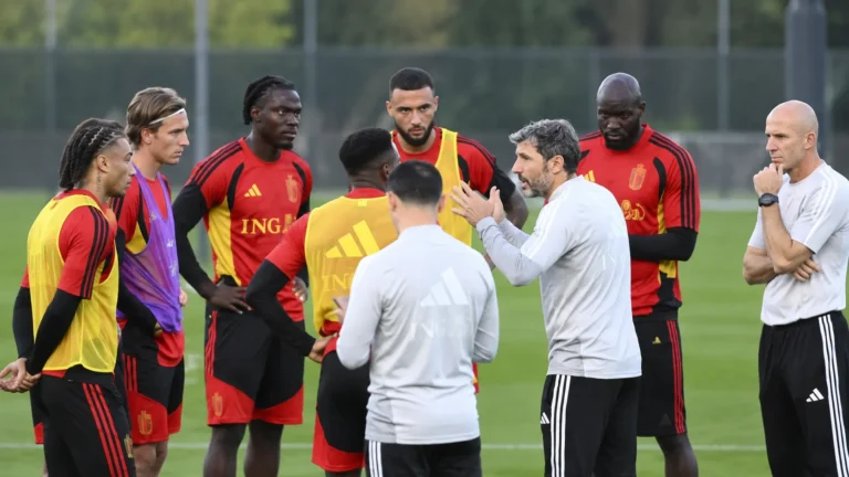 Stafleden spreken met een groep Rode Duivels op het trainingsveld.