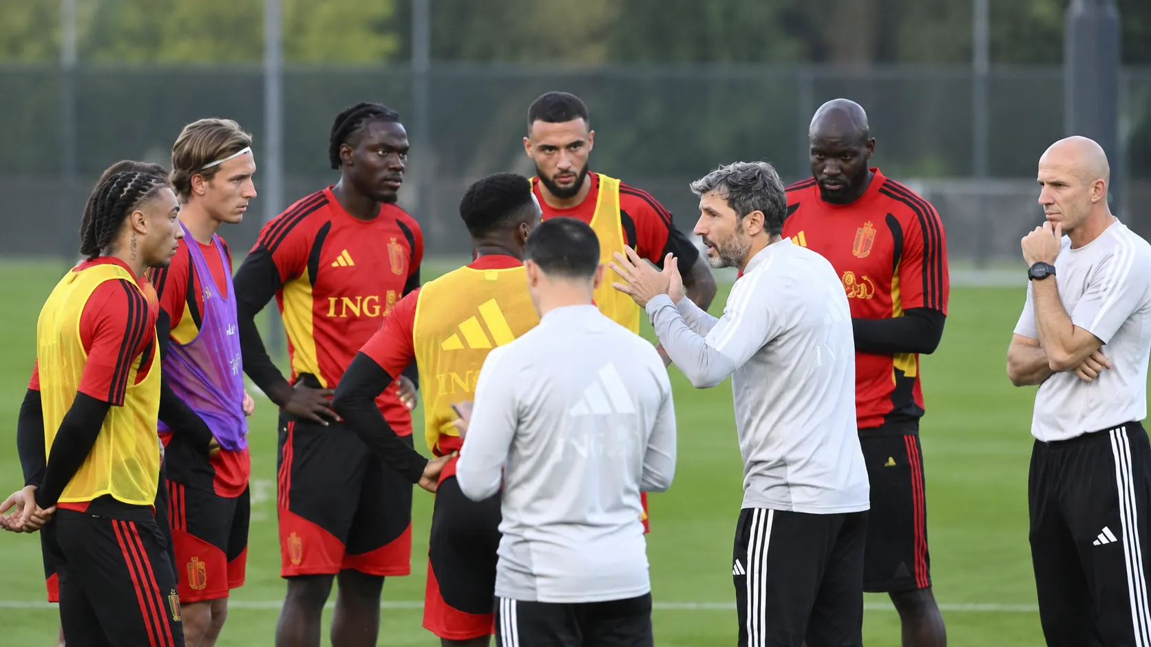 Stafleden spreken met een groep Rode Duivels op het trainingsveld.