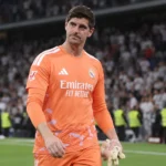 Thibaut Courtois in oranje doelmanstenue op het veld na een wedstrijd.