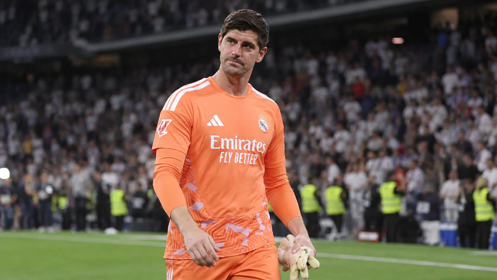 Thibaut Courtois in oranje doelmanstenue op het veld na een wedstrijd.