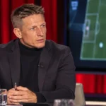 Wesley Sonck aan een tafel in een televisiestudio tijdens een voetbalanalyse.