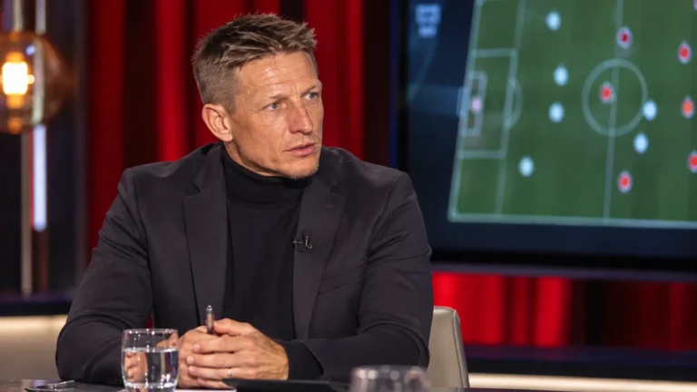 Wesley Sonck aan een tafel in een televisiestudio tijdens een voetbalanalyse.