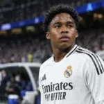 Endrick in het witte tenue van Real Madrid langs de zijlijn van een stadion.