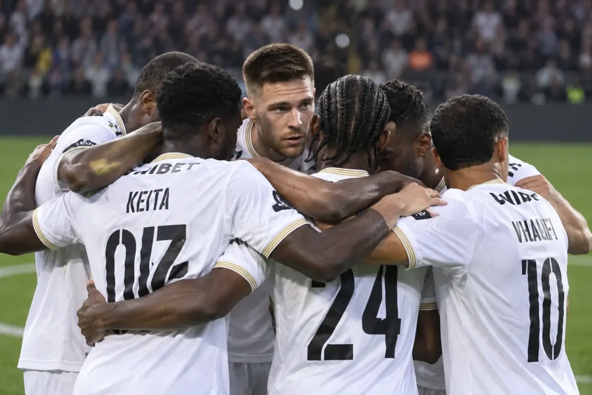 Een groep spelers van Sporting Charleroi in witte shirts tijdens een gezamenlijke huddle op het veld.
