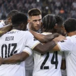 Een groep spelers van Sporting Charleroi in witte shirts tijdens een gezamenlijke huddle op het veld.