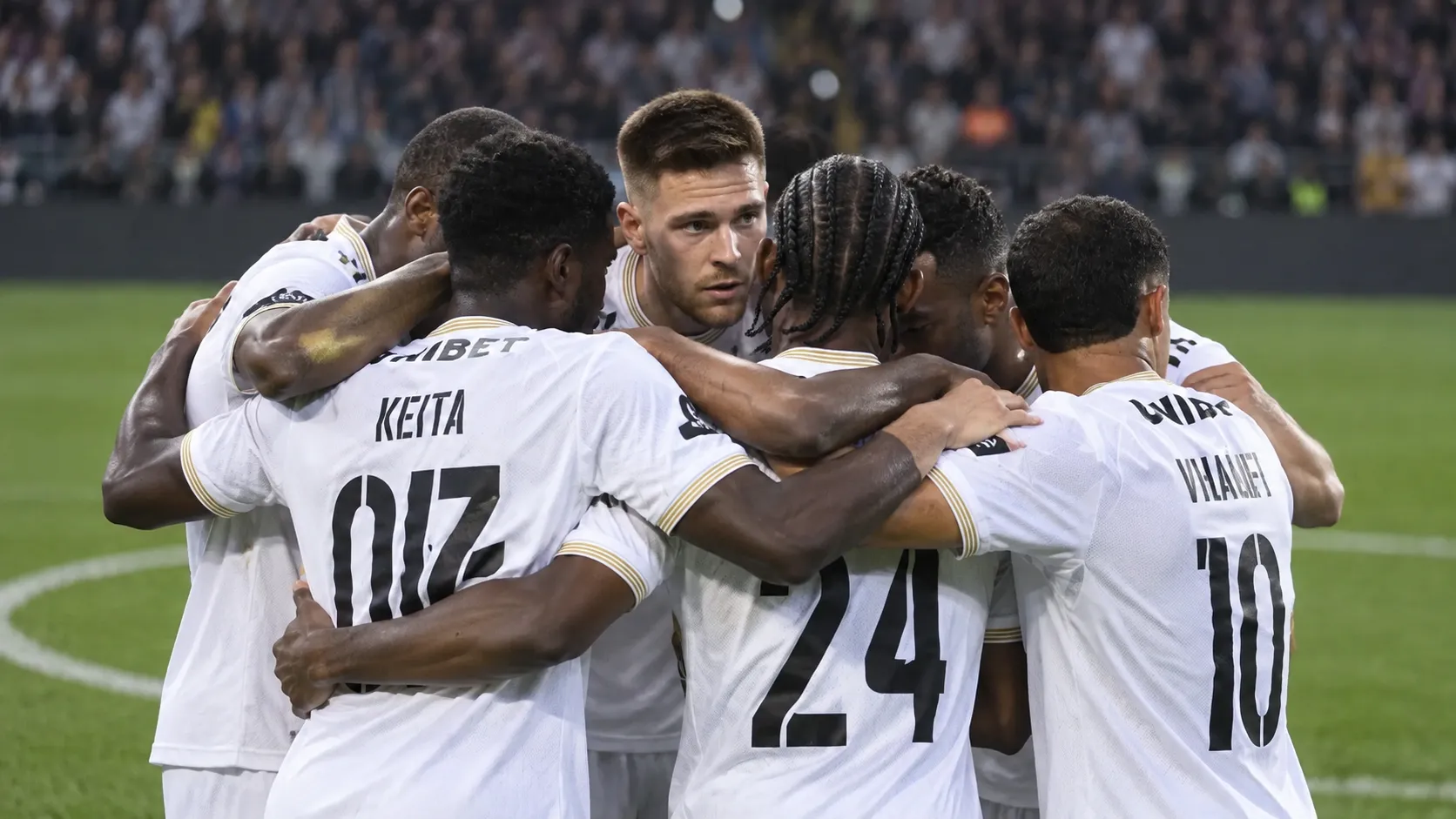 Een groep spelers van Sporting Charleroi in witte shirts tijdens een gezamenlijke huddle op het veld.