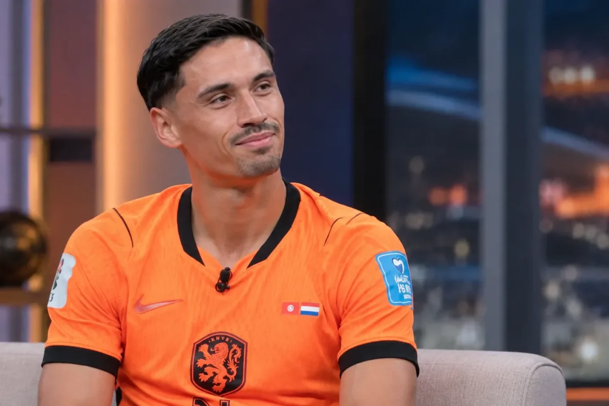 Tijjani Reijnders in een oranje voetbalshirt tijdens een rustig televisiegesprek.