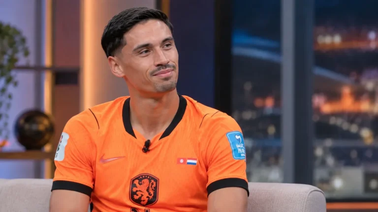 Tijjani Reijnders in een oranje voetbalshirt tijdens een rustig televisiegesprek.