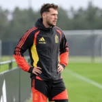 Lucas Stassin in Belgische trainingskleding aan de rand van een trainingsveld.