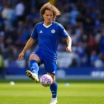 Wout Faes in een blauw wedstrijdshirt op het voetbalveld.