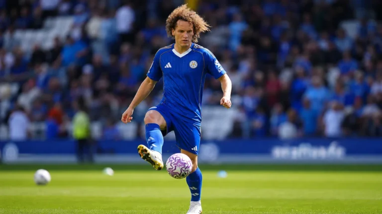 Wout Faes in een blauw wedstrijdshirt op het voetbalveld.