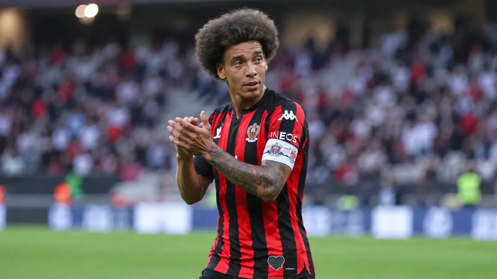 Axel Witsel met aanvoerdersband in het zwart-rode tenue van OGC Nice op het veld.
