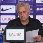 Javier Tebas aan een La Liga-perstafel terwijl hij notities bekijkt.