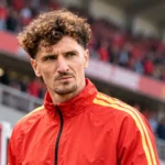 Thomas Meunier in een rode trainingsjas van de Belgische nationale ploeg in een stadion.