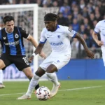 Voetballers strijden om de bal tijdens een wedstrijd in een Belgisch stadion.