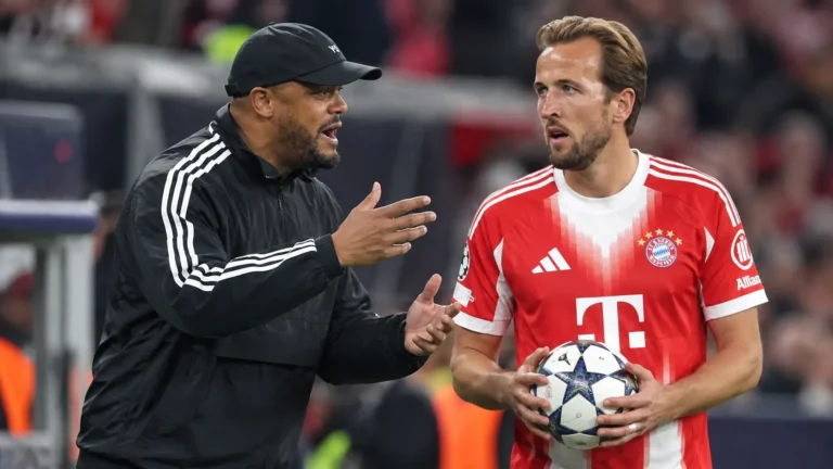 Een Bayern München-coach en een speler in rood tenue aan de zijlijn van een stadion.