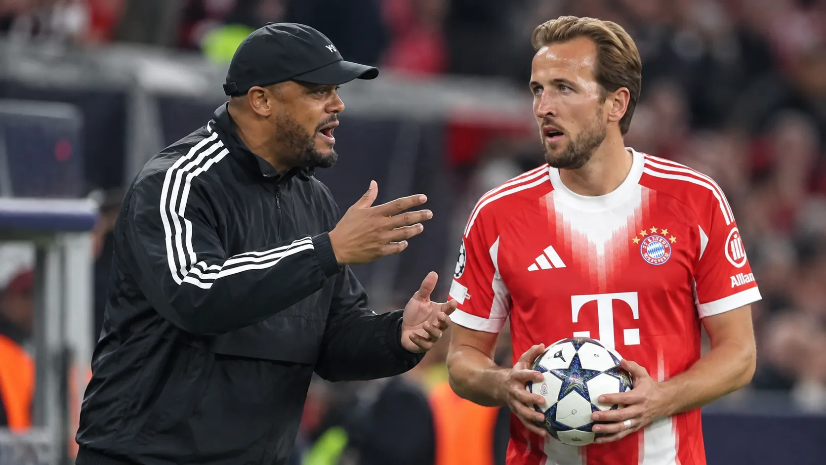 Een Bayern München-coach en een speler in rood tenue aan de zijlijn van een stadion.