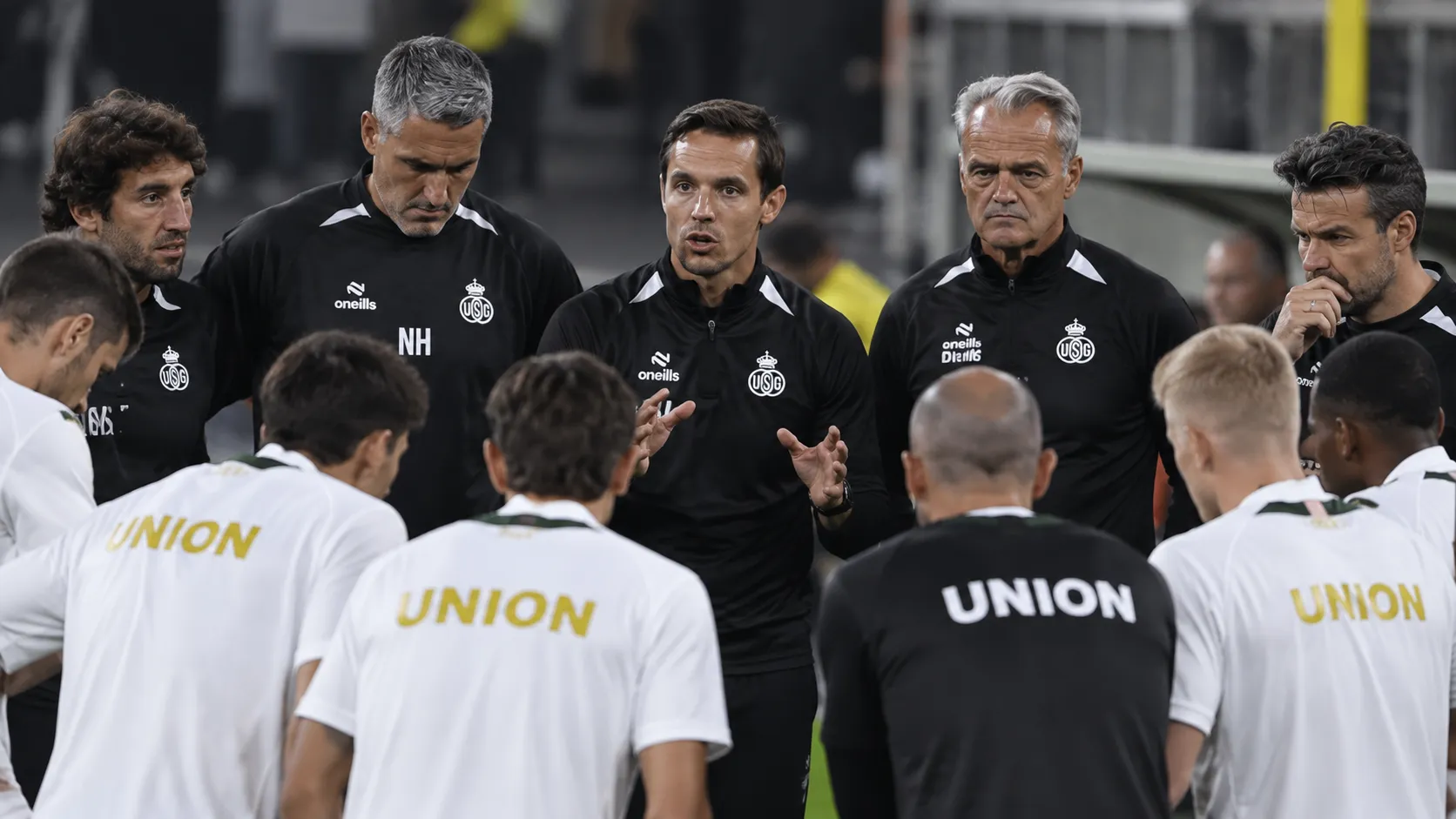 Spelers en stafleden van Union SG vormen een hechte kring aan de rand van het veld.