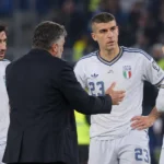 Italiaanse internationals in witte tenues overleggen langs het veld.