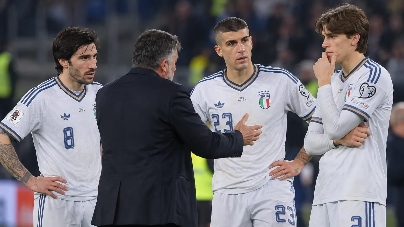 Italiaanse internationals in witte tenues overleggen langs het veld.