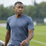 David Alaba in neutrale sportkleding naast een rustig trainingsveld.