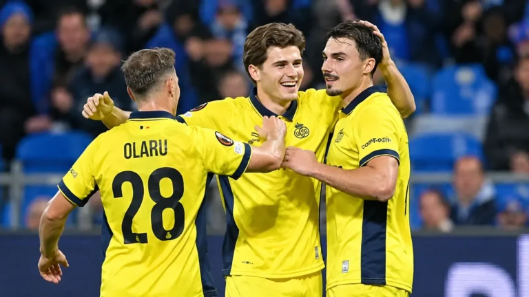 Drie voetballers in gele shirts vieren samen tijdens een wedstrijd.