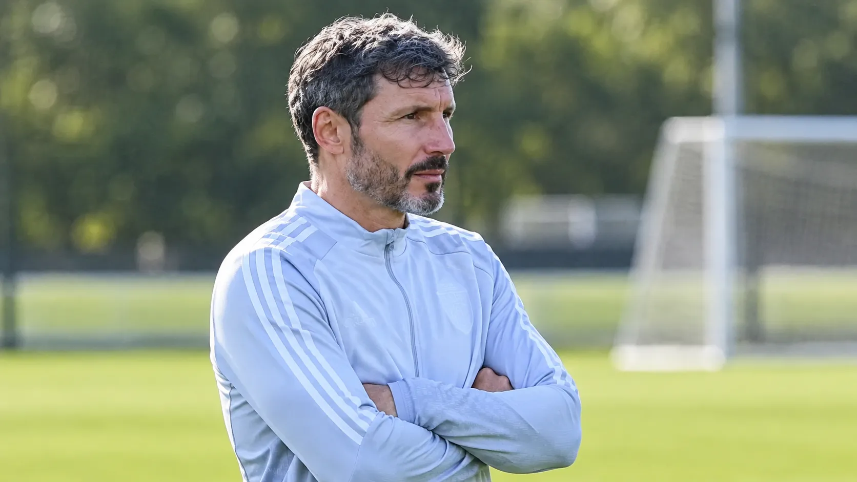 Mark van Bommel kijkt geconcentreerd toe langs een trainingsveld.