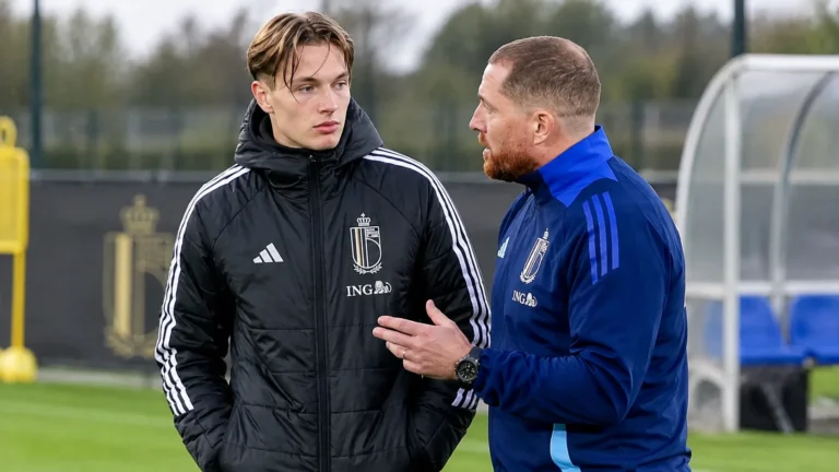 Een jonge speler en een staflid van de Belgische U21 overleggen langs de zijlijn.