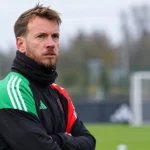 Neto in sportieve keeperskleding naast een voetbalveld.