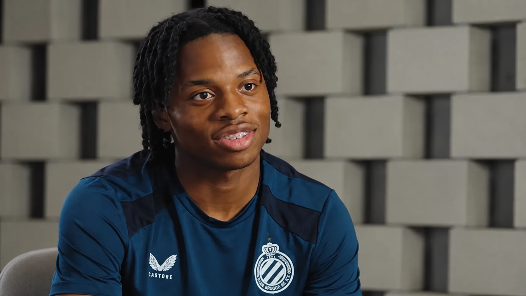 Wisdom Mike tijdens een interview in een donkerblauw Club Brugge-shirt.
