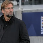 Jürgen Klopp in een rustige technische zone van een stadion naast een discreet Nations League-bord.