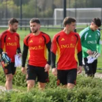 Een groep Rode Duivels in trainingskleding wandelt langs het trainingsveld.