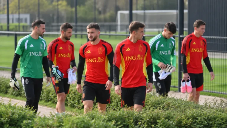 Een groep Rode Duivels in trainingskleding wandelt langs het trainingsveld.