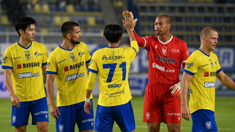 STVV-spelers in gele tenues en hun doelman vieren samen op het veld.
