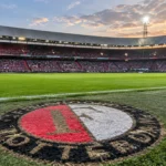 Het Feyenoord-embleem in de grasmat langs een leeg deel van het veld.