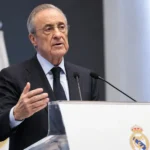 Een niet-spelende clubofficial spreekt aan een podium met zichtbaar Real Madrid-embleem.
