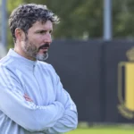 Mark van Bommel kijkt toe op het trainingsveld in Tubeke, met een vast Rode Duivels-bord op de achtergrond.