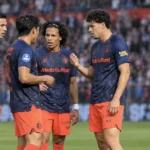 Een groep Feyenoord-spelers overlegt kort op het veld tijdens een wedstrijd.