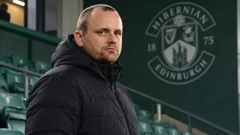 Reedijk in een neutrale jas voor een vast Hibernian-clubembleem in het stadion.