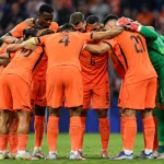 Nederlandse spelers in oranje vormen samen een kring op het veld.