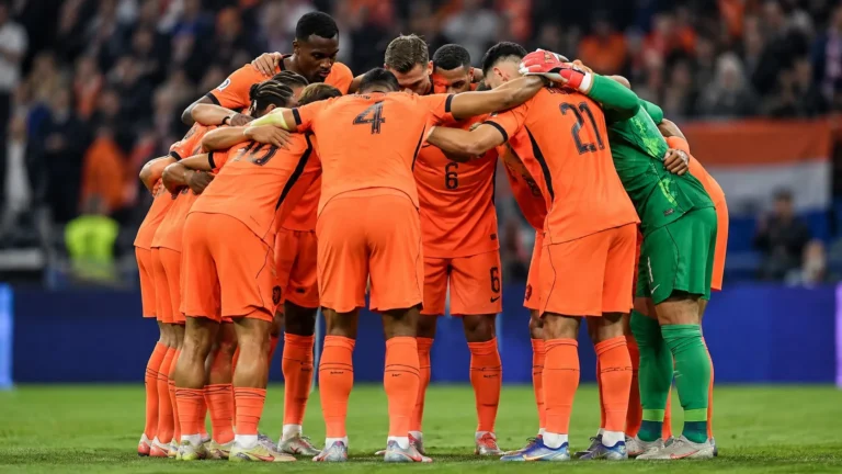 Nederlandse spelers in oranje vormen samen een kring op het veld.