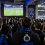 Een collectieve groep Club Brugge-supporters kijkt in de Noordtribune naar een groot scherm.